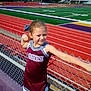 April is registered to the contest to win money with this photo: child, cheerleader, uniform, maroon, gray, chain_link_fence, football_field, goalpost, track, outdoor, daylight, posing, smiling, young_girl, sports, athlete, team, hair_bow, grass, stadium
