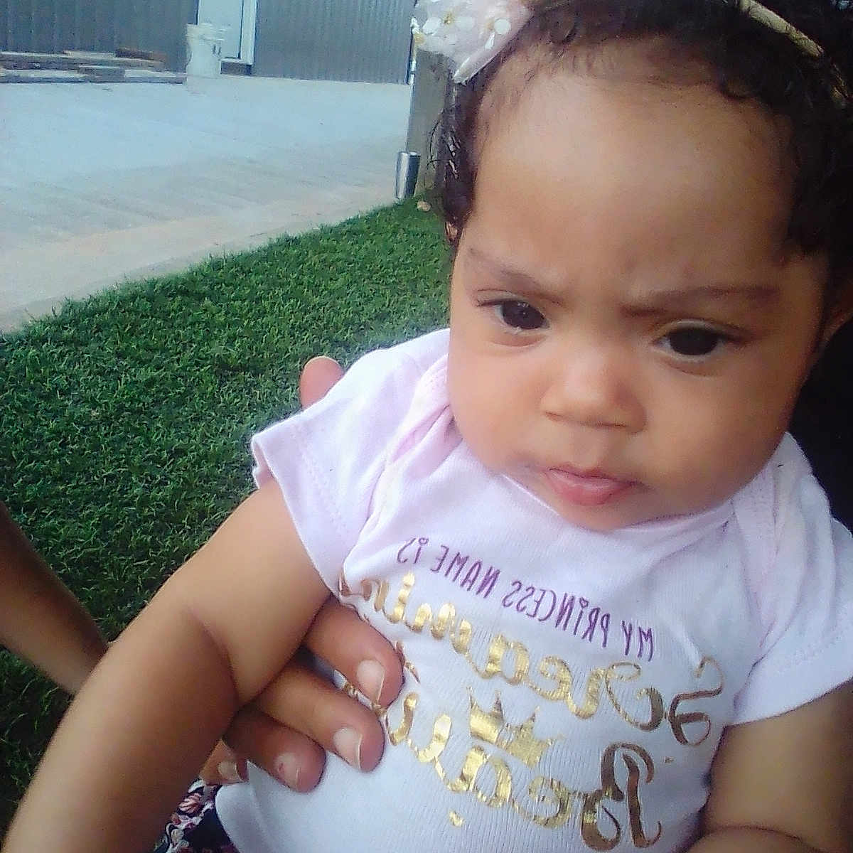 Mellissia joined the competition — help win amazing prizes! baby, casual_clothing, child, closeup, curly_hair, cute, expression, face, girl, grass, hand, headband, holding, infant, outdoor, person, pink_shirt, portrait, skin, young