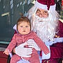 baby, child, santa_claus, red_suit, white_beard, glasses, pajamas, holiday, christmas, indoor, chair, gloves, face, person, seated, curious, festive, decoration, reflection, warmth