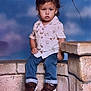 Gabriel is registered to the contest to win money with this photo: background, boy, casual_clothing, child, cute, expression, footwear, indoor, jeans, kite, portrait, shirt, shoes, short_hair, sitting, sky, stone_wall, studio, toddler, young_child