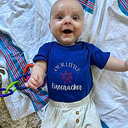 Alex is registered to the contest to win money with this photo: baby, blanket, blue_onesie, child, clothing, colorful, cute, expression, face, happy, indoors, infant, lying_down, person, playtime, reaching_out, small, smiling, toy, white_pants
