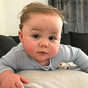 Mason is registered to the contest to win money with this photo: baby, child, face, hands, blanket, couch, curtains, indoor, clothing, striped_shirt, rosy_cheeks, tousled_hair, soft_texture, portrait, infant, cute, person, closeup, home, expression