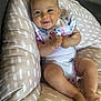 baby, infant, smile, cushion, floral_onesie, comfort, cute, chubby_cheeks, relaxing, indoors, soft_fabric, pattern, skin, person, happy, child, closeup, young, sitting, babywear