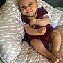 baby, smile, infant, cushion, pattern, maroon_clothing, cute, happy, indoor, skin, face, legs, feet, arm, hand, seated, child, person, soft_furniture, cozy