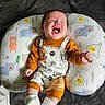baby, bear_pattern, child, clothing, colorful, cozy, cushion, cute, happy, indoor, infant, laughing, lying_down, onesie, playful, portrait, smiling, socks, soft_blanket, young