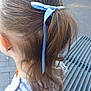 back_view, blue_ribbon, brick_wall, building, candid, casual, child, curly_hair, daylight, ear, fashion, hair, metal_grate, necklace, outdoor, person, ponytail, side_view, striped_clothing, young_child