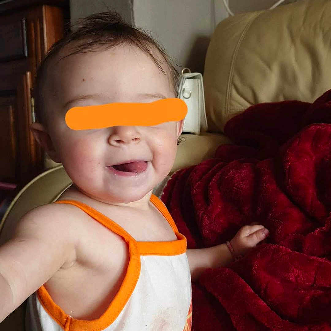 Lyllloo participe au concours pour gagner de l'argent avec cette photo : blanket, casual_clothing, child, couch, cozy, cute, face, furniture, happy, home, indoor, infant, person, red_blanket, sitting, smiling, tank_top, toddler, tongue_out, young_child