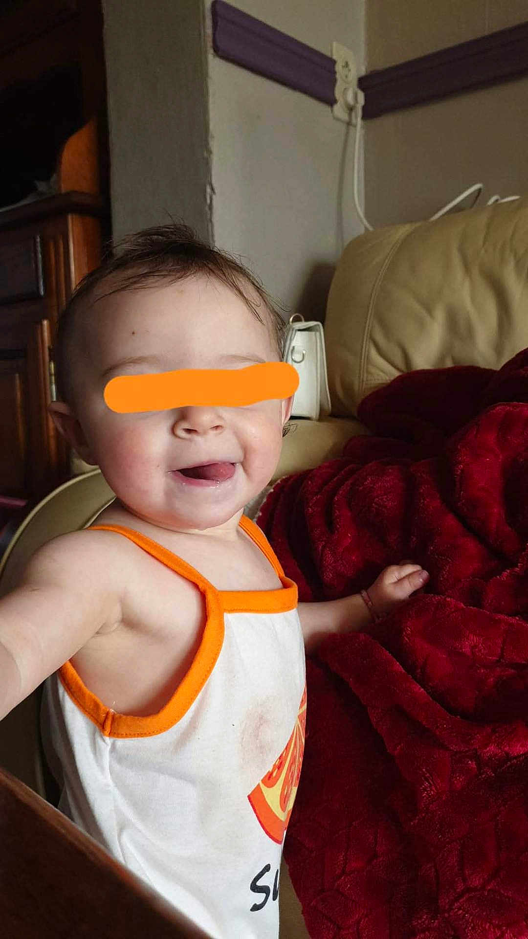 Lyllloo participe au concours pour gagner de l'argent avec cette photo : blanket, casual_clothing, child, couch, cozy, cute, face, furniture, happy, home, indoor, infant, person, red_blanket, sitting, smiling, tank_top, toddler, tongue_out, young_child
