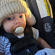 Andrew is registered to the contest to win money with this photo: baby, pacifier, car_seat, knit_hat, striped_shirt, blanket, snoopy, infant, child, seatbelt, closeup, cute, face, eyes, clothing, indoors, portrait, safety, sunlight, resting