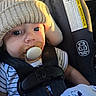 baby, pacifier, car_seat, knit_hat, striped_shirt, blanket, snoopy, infant, child, seatbelt, closeup, cute, face, eyes, clothing, indoors, portrait, safety, sunlight, resting