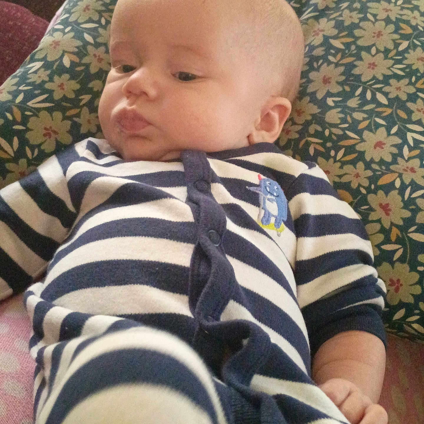 Robby joined the competition — help win amazing prizes! baby, child, comfort, couch, cute, face, floral_pattern, hand, head, indoors, infant, onesie, person, pillow, relaxing, skin, sleepwear, soft, striped_clothing, young