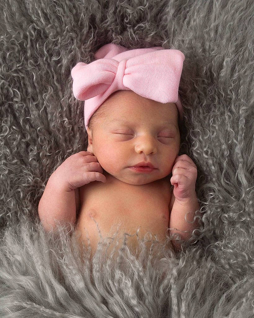 Charity is registered to the contest to win money with this photo: baby, beanie, bonnet, cap, cheek, child, costume_accessory, fashion_accessory, fur, hair_accessory, hand, headgear, person, photography, pink, portrait_photography, skin, toddler