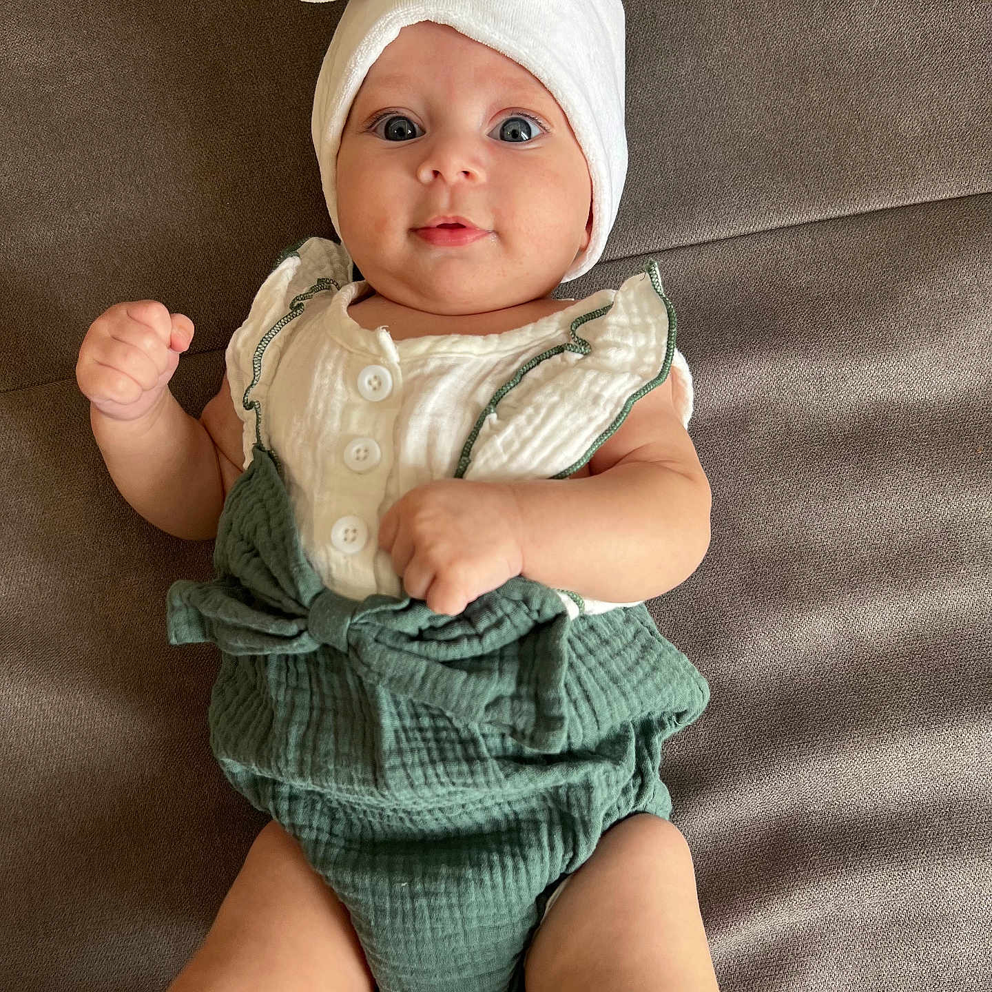 Naïssya participe au concours pour gagner de l'argent avec cette photo : baby, baby_fashion, bow, child, clothing, cute, eyes, gray_background, green_outfit, hands, headwrap, indoor, infant, legs, lying_down, portrait, skin, smile, soft_surface, white_top
