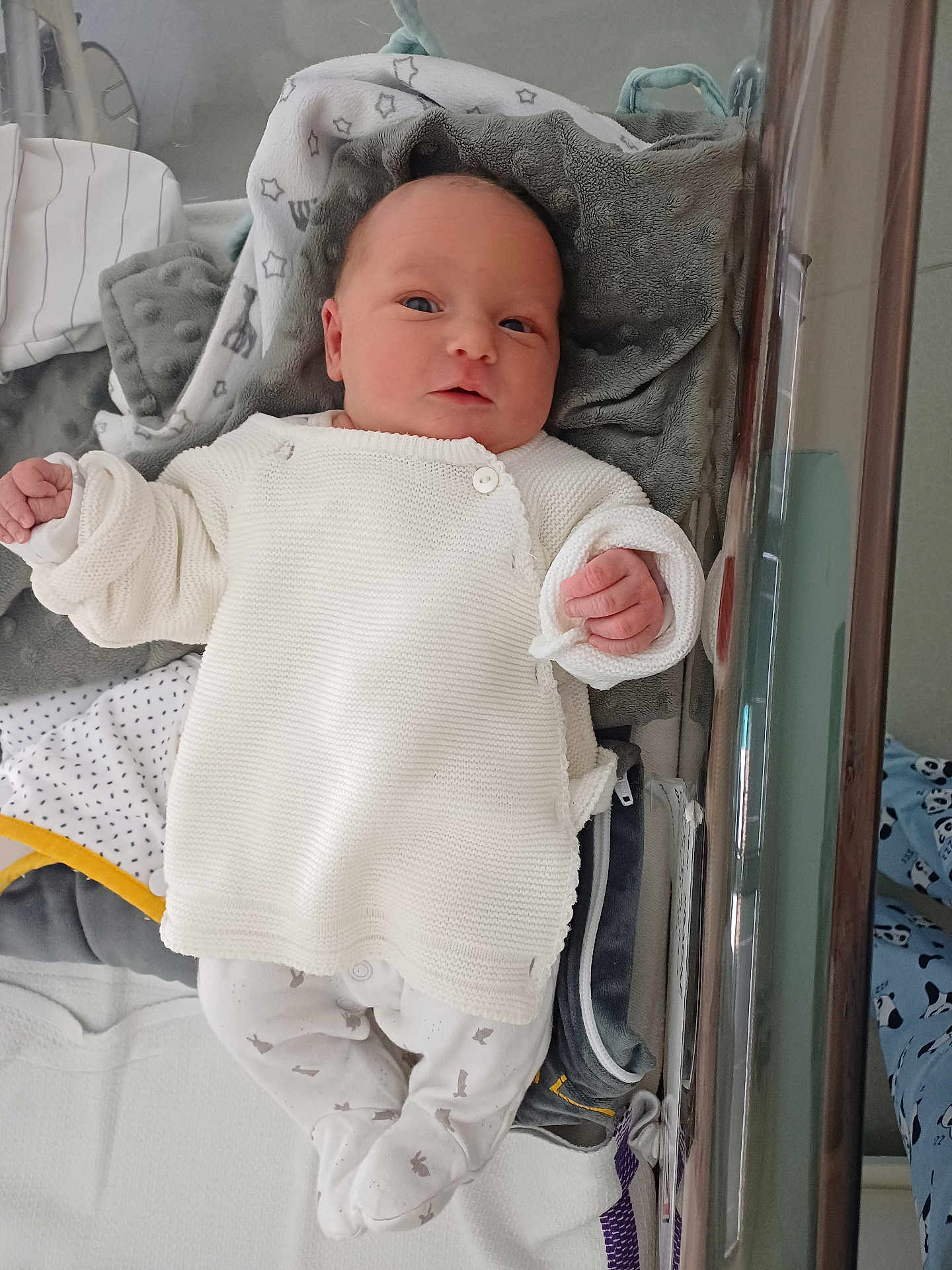 Théa participe au concours pour gagner de l'argent avec cette photo : baby, newborn, infant, crib, blanket, white_clothing, knitted, sleepwear, soft_toys, bed, child, cute, person, indoors, resting, warm, cozy, small_hands, portrait, infant_clothing