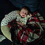 Donald is registered to the contest to win money with this photo: baby, sleeping, blanket, plaid, bib, cushion, infant, resting, cozy, comfort, face, indoor, child, soft, toddler, nap, peaceful, clothing, dark, sofa