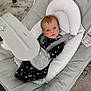 baby, infant, baby_seat, onesie, stars_pattern, face, eyes, head_support, straps, cushion, carpet, floor, indoors, baby_gear, baby_bouncer, child, person, cute, comfort, resting