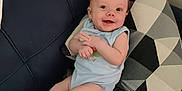 Donald is registered to the contest to win money with this photo: baby, smiling, couch, pillow, blanket, infant, happy, indoors, child, blue_clothing, geometric_pattern, relaxing, comfortable, cute, young_child, face, small_hands, barefoot, seated, home