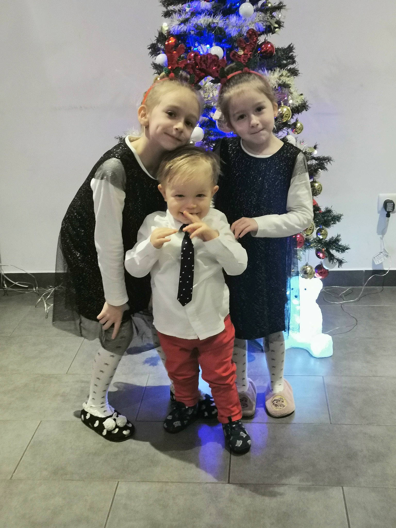 Tiffany participe au concours pour gagner de l'argent avec cette photo : baby_toddler_clothing, child, christmas_decoration, christmas_eve, christmas_lights, christmas_ornament, christmas_tree, face, family, floor, holiday, human_body, joy, ornament, person, purple, roller_skates, sock, standing, toddler