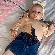 Myla a rejoint le concours — aidez-le/la à gagner de superbes lots ! baby, child, face, headband, bow, clothing, denim, shorts, tights, bedspread, pattern, pink, white, blue, person, infant, cute, lying_down, looking, indoor