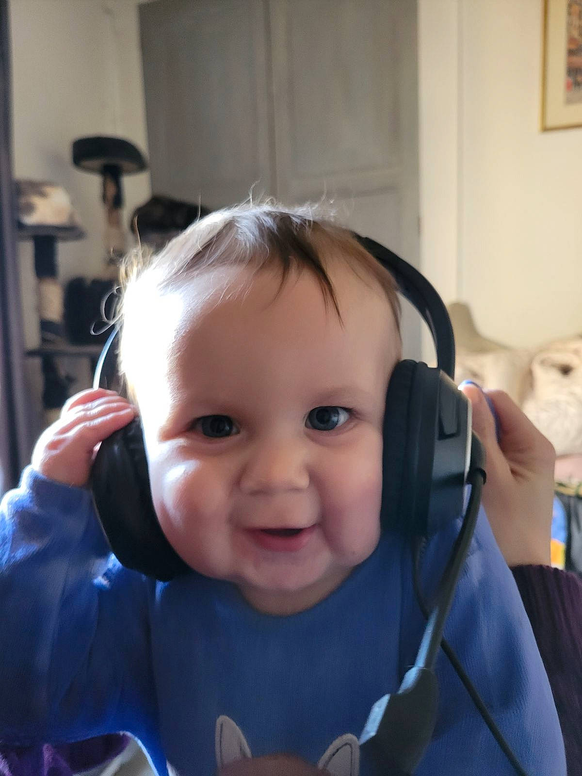 architecture, baby, clothing, coat, electronics, face, happy, head, headphones, indoors, jacket, laughing, lighting, person, photography, plant, portrait, pottedplant, smile, t_shirt