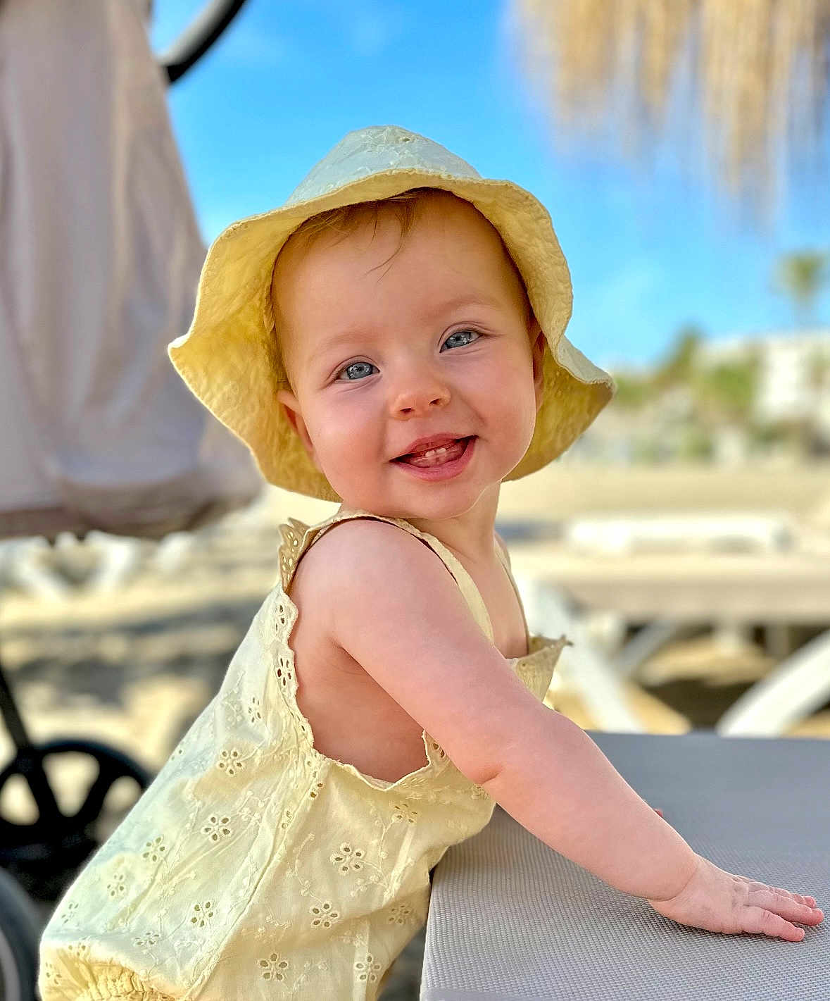 Imogen joined the competition — help win amazing prizes! baby, child, smiling, yellow_hat, yellow_dress, sunhat, outdoor, beach, table, blue_sky, portrait, happy, cute, infant, summer, sunny, daytime, closeup, person, leisure