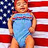 Hallie joined the competition — help win amazing prizes! baby, infant, smiling, red_bow, blue_striped_outfit, american_flag, patriotic, happy, cute, child, portrait, lying_down, colorful, celebration, holiday, summer, warm, skin, face, headwear