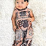 baby, infant, child, black_bow, patterned_clothing, lying_down, fluffy_rug, white_background, cute, portrait, fashion, foot, hand, smile, indoors, soft_texture, young_child, headwear, person, comfortable