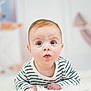 baby, child, closeup, curious, cute, expression, eyes, face, fluffy_surface, hands, head, indoor, infant, lying_down, person, portrait, skin, soft_background, striped_shirt, young