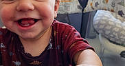 Harper joined the competition — help win amazing prizes! baby, child, infant, smiling, happy, portrait, close_up, face, eyes, teeth, blond_hair, red_shirt, patterned_clothing, hand, playpen, play_yard, indoor, window, daylight, candid