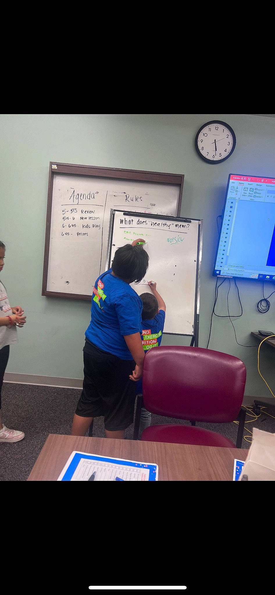 Izaac is registered to the contest to win money with this photo: class, clock, collaboration, desk, display_device, employment, event, font, handwriting, job, learning, office_supplies, person, presentation, room, service, t_shirt, table, training, visual_arts