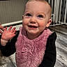 Aliyah joined the competition — help win amazing prizes! toddler, child, smile, happy, indoor, floor, bib, pink, black_clothing, barefoot, face, person, home, wood_floor, window_blinds, baby_gate, cute, young_child, standing, expression