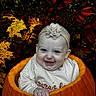 Aliyah is registered to the contest to win money with this photo: baby, child, pumpkin, autumn, fall_leaves, orange, smile, headband, flower, cute, seasonal, nature, outdoor, happy, portrait, sitting, holiday, festive, person, celebration