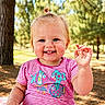 Sarah is registered to the contest to win money with this photo: toddler, child, baby, smiling, waving, outdoor, nature, trees, pine_trees, pink_shirt, striped_shirt, fish_print, hair_tie, topknot, blanket, sunlight, happy, cute, portrait, sitting