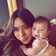 Clementine is registered to the contest to win money with this photo: woman, baby, smile, face, hair, arm, couch, indoor, portrait, holding, happy, person, clothing, skin, wood, furniture, closeup, baby_girl, casual, cozy