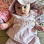 baby, child, pink_clothing, hat, mittens, floral_blanket, cute, portrait, indoor, infant, soft_fabric, wide_eyes, sitting, closeup, adorable, young_child, baby_girl, cozy, expression, face