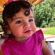 Liliana is registered to the contest to win money with this photo: toddler, child, curly_hair, pink_dress, outdoor, portrait, cute, smiling, earrings, ribbon, daylight, nature, pavilion, bench, greenery, face, person, happy, young_child, closeup