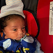 Stephen joined the competition — help win amazing prizes! newborn, baby, infant, hat, blue_clothing, blanket, baby_carrier, face, eyes, closeup, indoor, colorful, striped_hat, soft_texture, red_background, cute, portrait, child, sleepwear, cozy