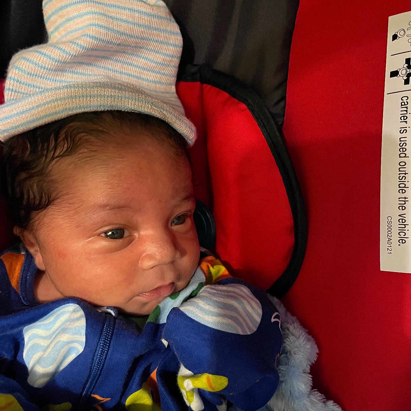 Stephen joined the competition — help win amazing prizes! baby, baby_carrier, blanket, blue_clothing, child, closeup, colorful, cozy, cute, eyes, face, hat, indoor, infant, newborn, portrait, red_background, sleepwear, soft_texture, striped_hat