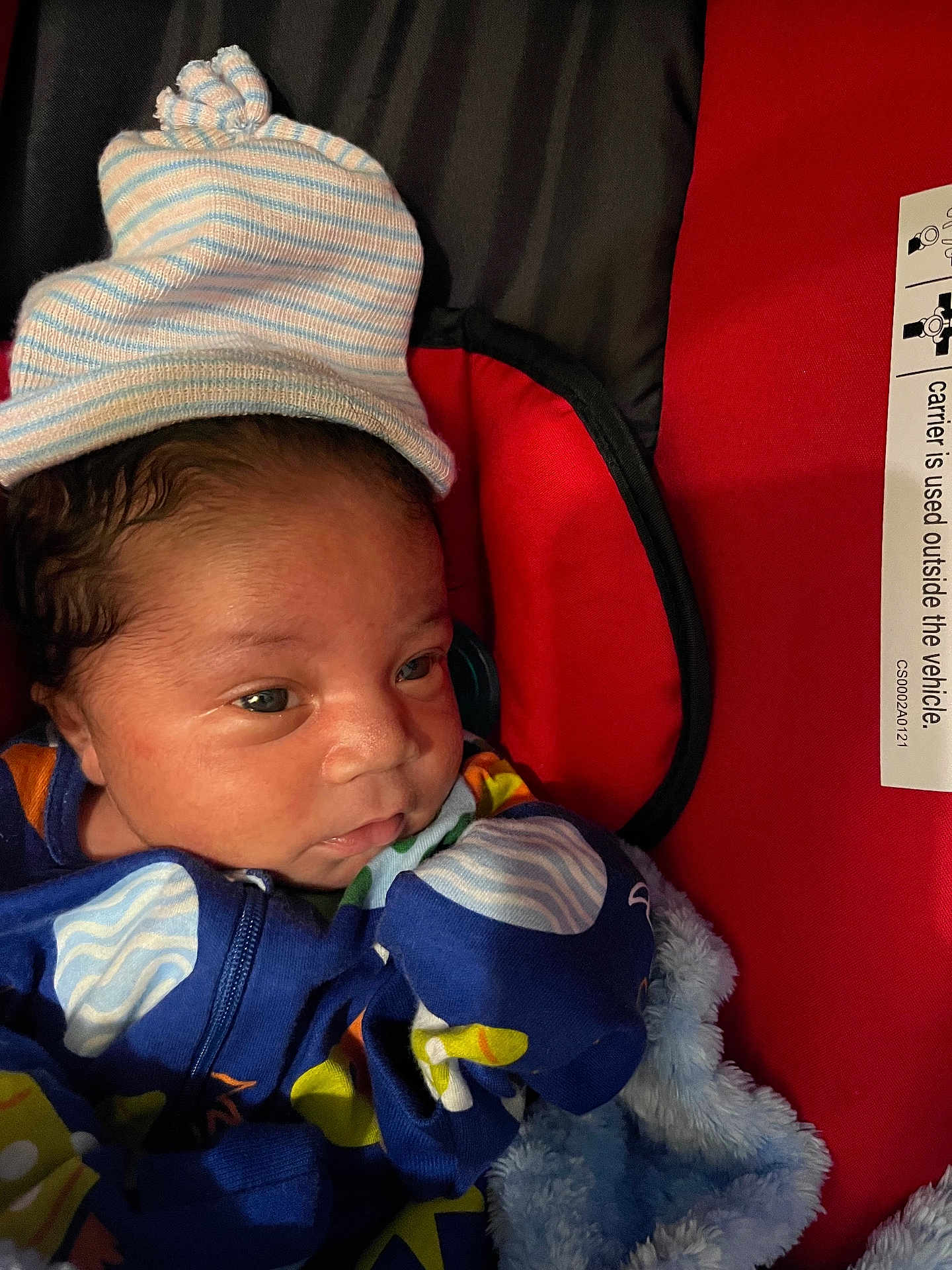 Stephen joined the competition — help win amazing prizes! newborn, baby, infant, hat, blue_clothing, blanket, baby_carrier, face, eyes, closeup, indoor, colorful, striped_hat, soft_texture, red_background, cute, portrait, child, sleepwear, cozy