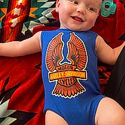 Carson joined the competition — help win amazing prizes! baby, infant, smile, blue_onesie, harley_davidson, blanket, patterned_blanket, teether, toy, lying_down, happy, face, arm, leg, skin, cute, child, portrait, indoor, clothing