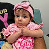 baby, infant, child, portrait, face, eyes, wide_eyed, pink, striped_clothing, headband, bow, sitting, held, adult, arms, hands, indoors, chair, smiling, photography