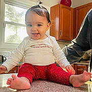 Renesmee joined the competition — help win amazing prizes! baby, cabinet, child, countertop, cute, foot, hair_bow, happy, home, indoor, infant, kitchen, natural_light, person, red_pants, sitting, smiling, toddler, white_shirt, window