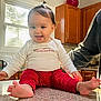 baby, cabinet, child, countertop, cute, foot, hair_bow, happy, home, indoor, infant, kitchen, natural_light, person, red_pants, sitting, smiling, toddler, white_shirt, window