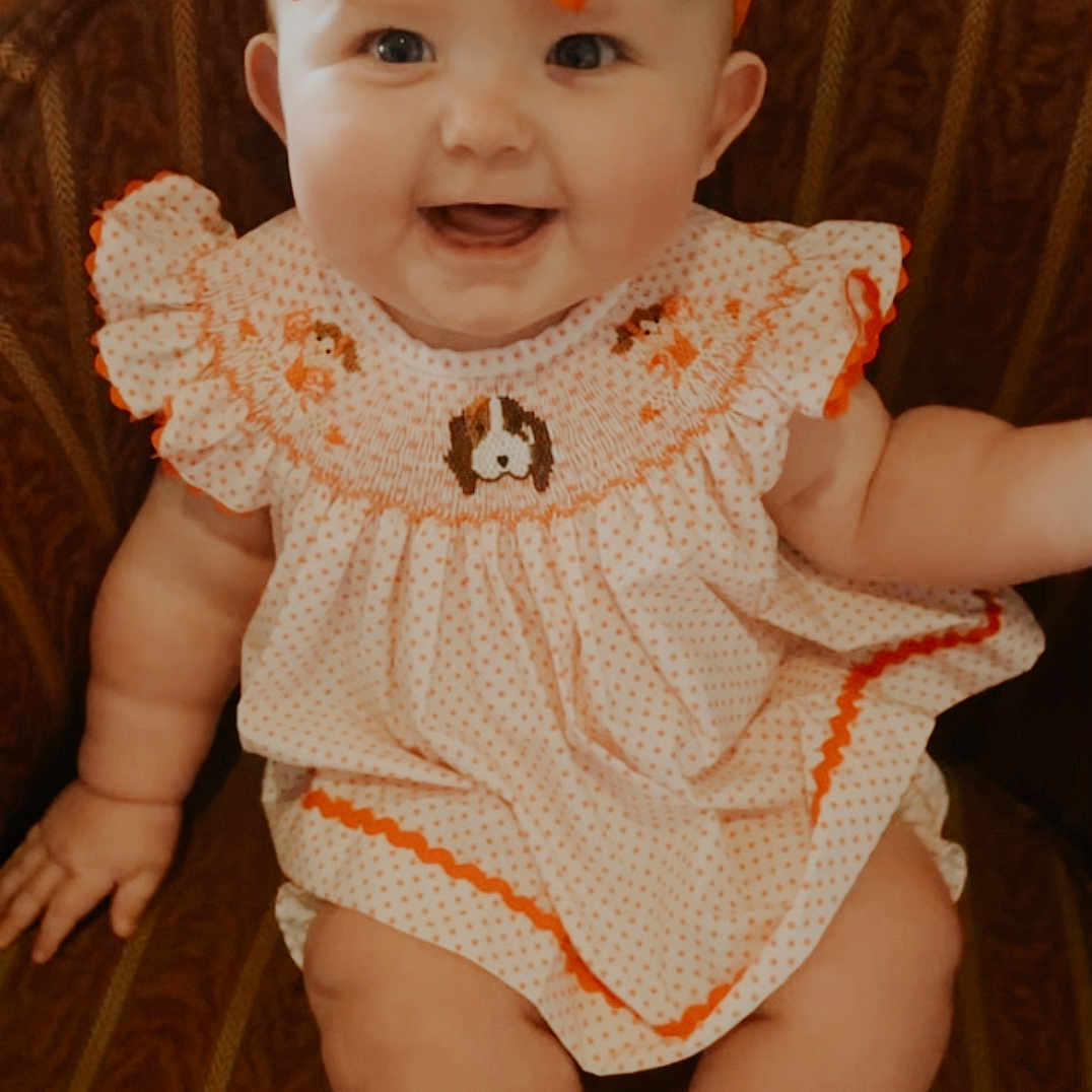 Olivia joined the competition — help win amazing prizes! accessories, baby, babylaughing, bonnet, cap, chair, clothing, costume, couch, dress, face, furniture, happy, hat, head, person, photography, portrait, sitting, smile
