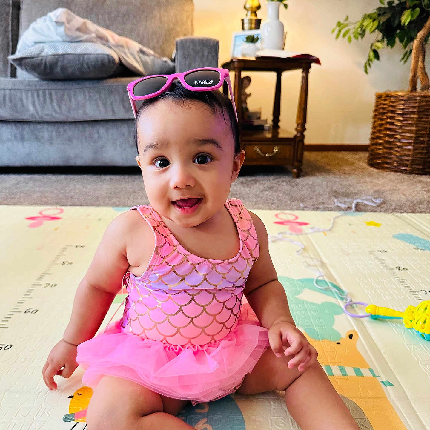 Azlin Mehrish is registered to the contest to win money with this photo: baby, child, cute, floor, happy, indoor, lamp, living_room, pink_clothing, plant, play_mat, portrait, sitting, smiling, sofa, sunglasses, table, toy, tutu, young_child