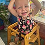 toddler, child, smiling, high_chair, wooden_chair, indoor, plant, flower_pattern, shoes, happy, person, face, table, furniture, colorful, playful, baby, cute, young_child, room