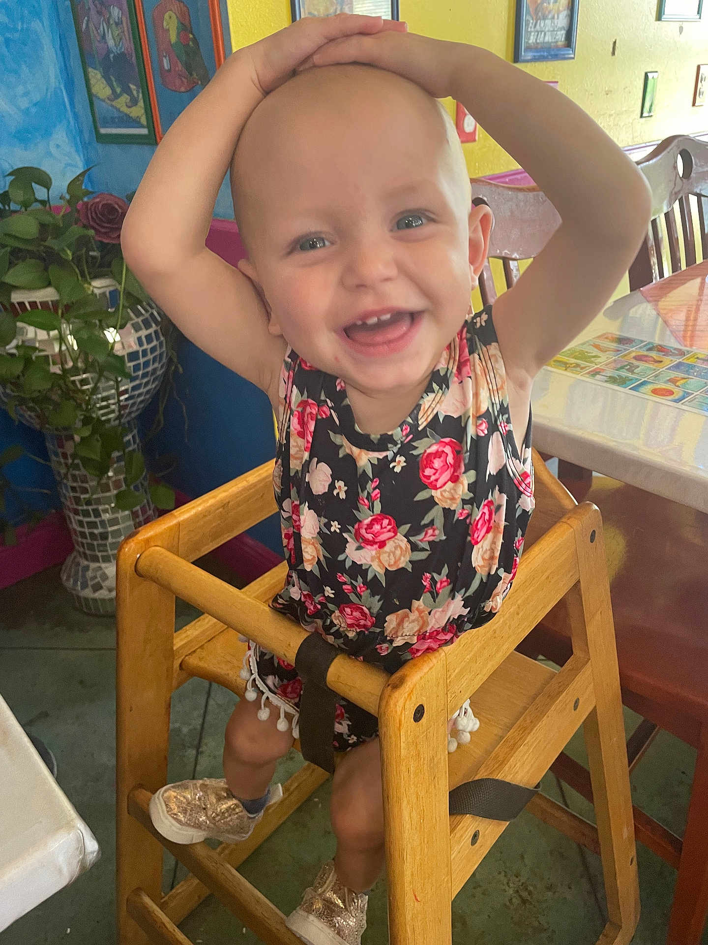 Isabella joined the competition — help win amazing prizes! toddler, child, smiling, high_chair, wooden_chair, indoor, plant, flower_pattern, shoes, happy, person, face, table, furniture, colorful, playful, baby, cute, young_child, room