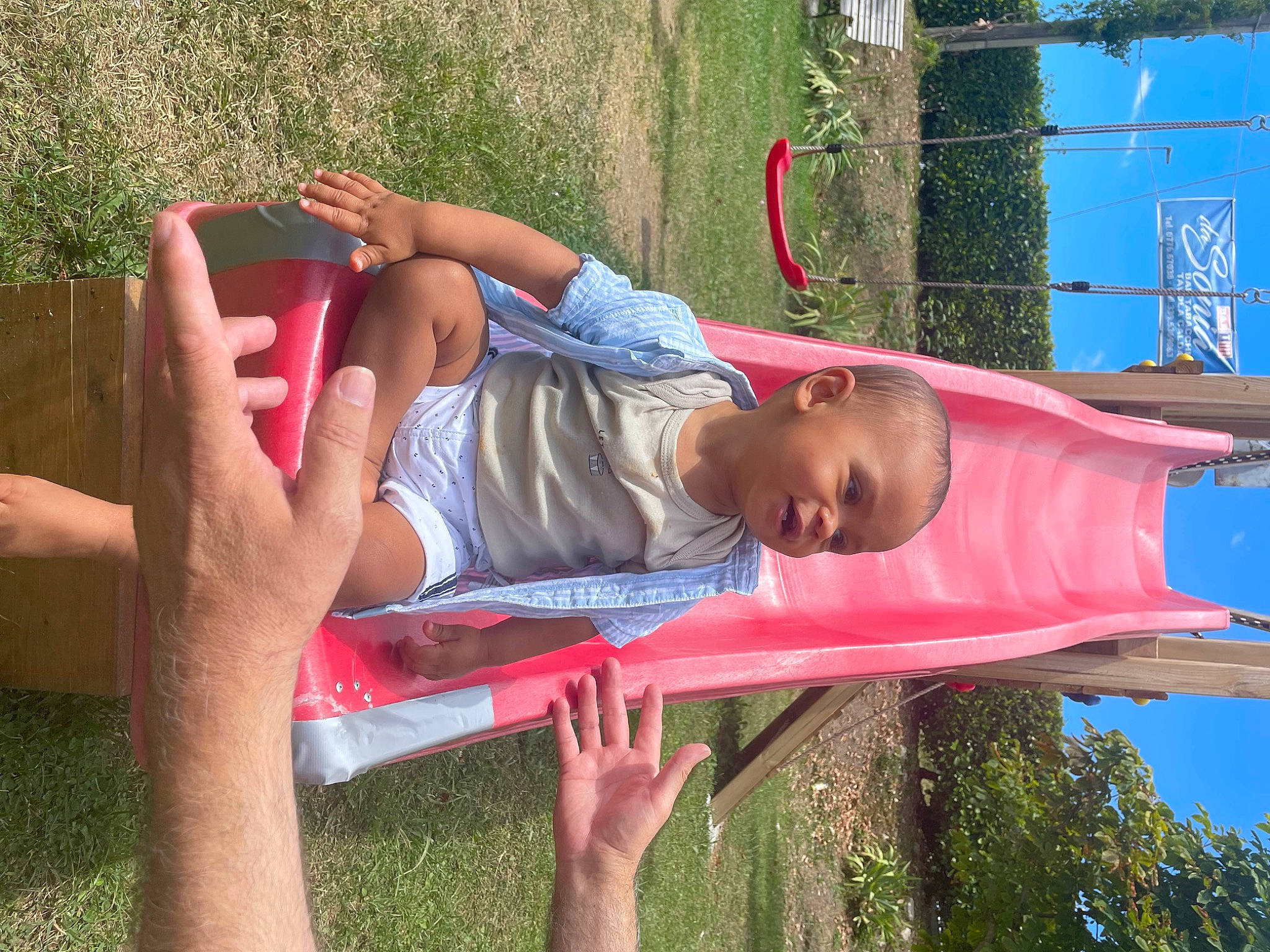 Ezra participe au concours pour gagner de l'argent avec cette photo : child, city, fun, grass, happy, leisure, outdoor_furniture, outdoor_play_equipment, people_in_nature, person, plant, recreation, red, shade, shorts, sitting, sky, spring, summer, toddler