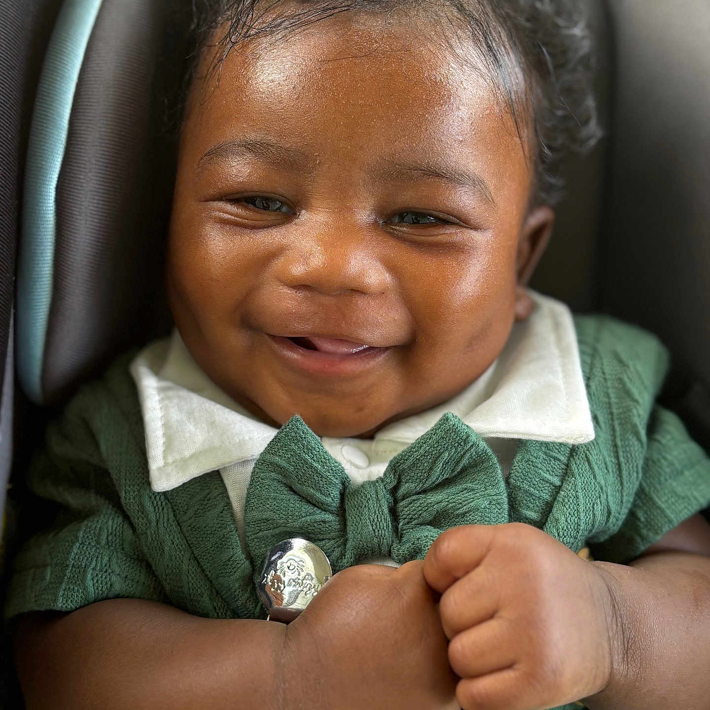 Harlem is registered to the contest to win money with this photo: adorable, baby, baby_accessory, car_seat, child, closeup, curly_hair, cute, face, green_clothing, hands, happy, holding, infant, knitwear, portrait, sitting, skin, smile, white_collar