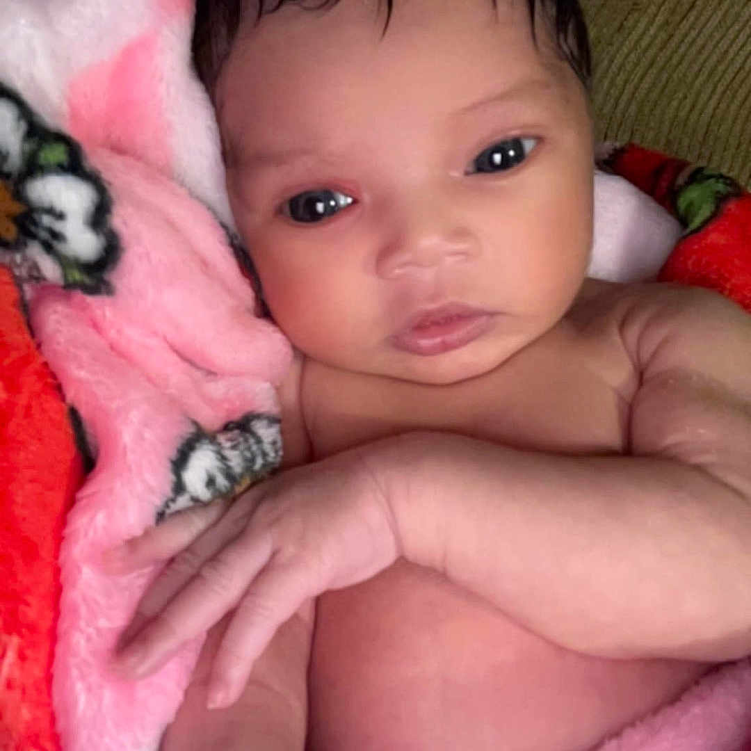 Vie Vie is registered to the contest to win money with this photo: baby, blanket, child, couch, cozy, cute, expression, face, hand, indoors, infant, newborn, pink, portrait, red, resting, skin, soft, wrapped, young